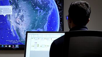 Engineer monitoring satellite tracking and signal-chain software on a lab workstation