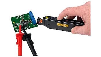 A technician using a current clamp to test the current on an electronic board