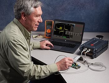 Engineer probing a circuit board while measuring signals with a Keysight bench setup