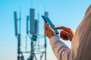 Someone using a mobile phone infront of a mobile phone antenna